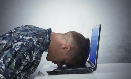 Right profile view of a sailor resting his head on a laptop sitting on a table