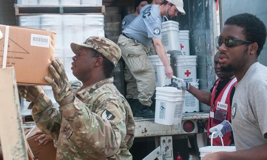 Soldiers load American Red Cross supplies with the help of volunteers from the Ameri­Corps National Civilian Community Corps. The thousands of young adults age 18 to 26 who complete national service with AmeriCorps have demonstrated a commitment to serve and are ready to learn more about the Sea Services.