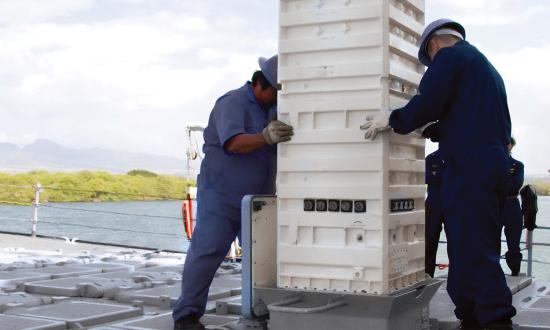 Sailors load a missile cannister into a Mk 41 vertical launch cell.