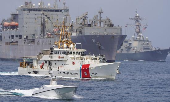 An unmanned surface vessel, the USCGC Charles Moulthrope (WPC-1141), the dry cargo and ammunition ship USNS Amelia Earhart (T-AKE-6), and the guided-missile destroyer USS Thomas Hudner (DDG-116) transit the Strait of Hormuz in August 2023. 