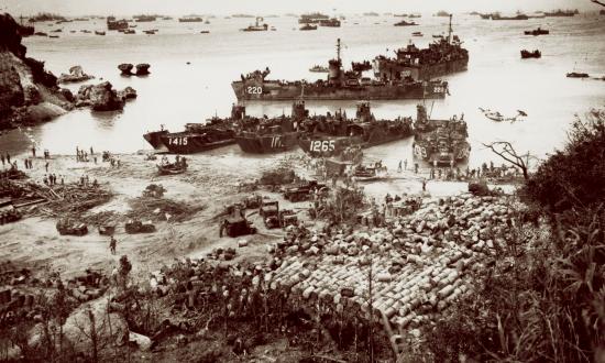 With ships out to the horizon as far as the eye can see, landing craft of the massive U.S. invasion armada pour out supplies and military equipment onto the beach at Okinawa in April 1945. From late 1944 into 1945, U.S. naval forces unleashed a “dazzling display of maritime power” while advancing toward Japan “with hardly a pause and without an important defeat.”