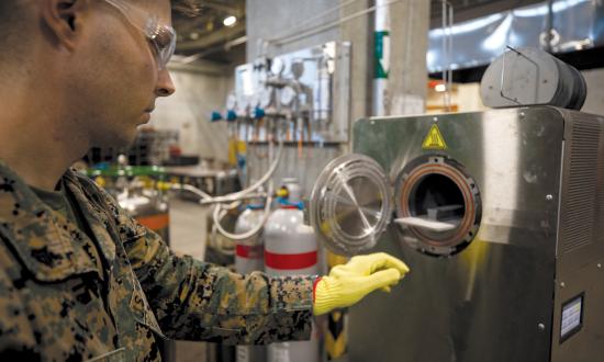 A Marine Corps corporal at Camp Kinser, Okinawa, places a 3-D printed part inside a sinter to bake and fuse. 