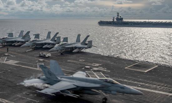An F-18 Super Hornet lands on board the USS Ronald Reagan (CVN-76) and the USS Nimitz (CVN-68) steams nearby in the South China Sea.  