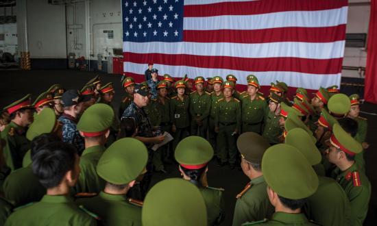 A USS Carl Vinson (CVN-70) sailor explains damage control capabilities to Vietnamese military officials during the ship’s 2018 port visit to Danang, Vietnam. Months of preparation and coordination at the highest levels of both the U.S. and Vietnamese governments were necessary to execute such a high profile and geopolitically sensitive event.