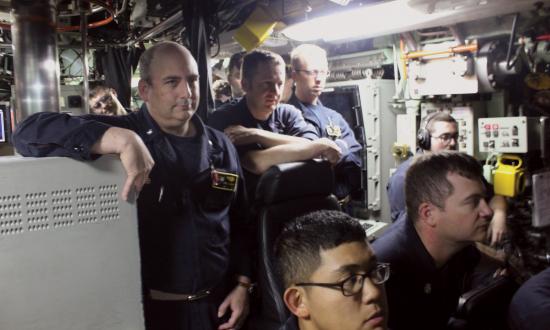 The commanding officer of the USS Pittsburgh (SSN-720) observes the officer of the deck and navigation control team as the submarine makes its 1,000th dive. A prospective OOD develops technical skills through years of training in high-tech classrooms, simulators, and prototype propulsion systems, but the interpersonal skills required to lead a watch team are not taught in any formal setting.