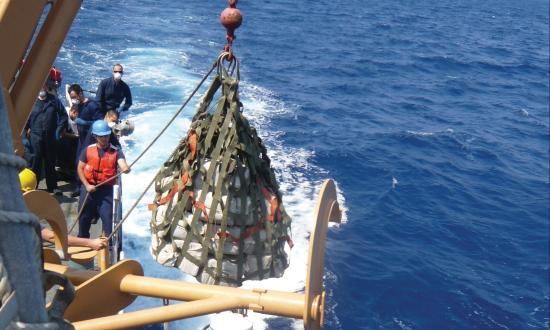 The crew of the Coast Guard Cutter Campbell lowers cocaine onto the small boat of the Coast Guard Cutter Dallas during a transfer of contraband while on patrol in the Caribbean Sea