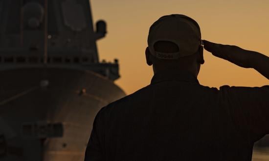 A sailor salutes the flag on board the USS Carney (DFG-64). The legacy of leaders is often in those they mentor—and those their mentees go on to lead in turn. 