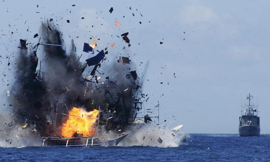 An Indonesian Navy vessel watches as a foreign boat caught fishing illegally in Indonesian waters near Bitung, North Sulawesi, is blown up. As recently as 2019, Indonesia has destroyed fishing boats found violating its exclusive economic zone.