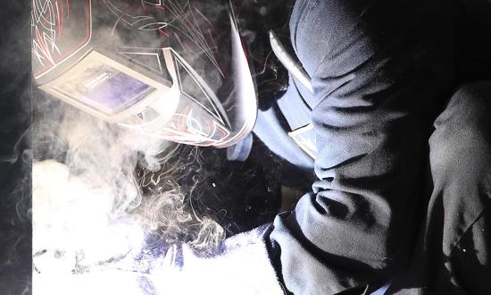 A hull maintenance technician works on the USS Tripoli (LHA-7). The United States must consider new strategies to address shipbuilding capacity. 