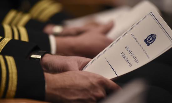 A U.S. Naval War College (NWC) student holds a program during his graduation ceremony held at NWC’s Spruance Auditorium. PME should be structured to promote warfare-focused intellectual skills.  