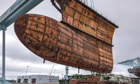 The final piece of the underwater hull of the aircraft carrier USS John F. Kennedy (CVN-79) being lowered into place in September 2019. The Navy needs to recapitalize the shipbuilding industry to produce the new capabilities and warships required to win the next war.