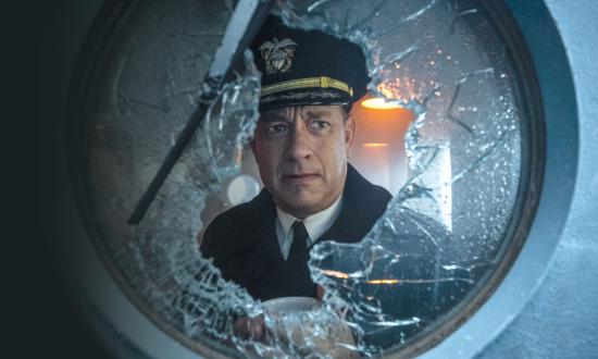 In Greyhound, Commander Ernest Krause (Tom Hanks) peers out through a shattered porthole in a scene that was likely shot on the film’s reproduction of the USS Kidd’s pilothouse.