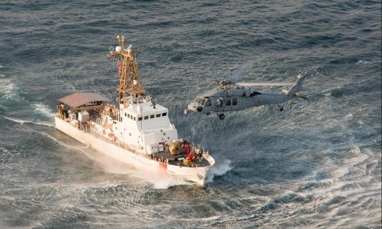 Aerial starboard bow view of USCGC Sapelo (WPB-1314) with a MH-60 Seahawk helicopter hovering over her bow.