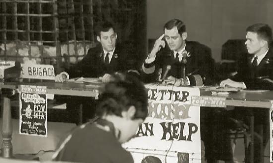 In fall 1970, the Naval Academy held a press conference on the plight of POW/MIA families. Midshipmen Rick Rubel and Joe Glover flank Brigade Commander Mike Hecomovich, with the replica bamboo cage in the background.