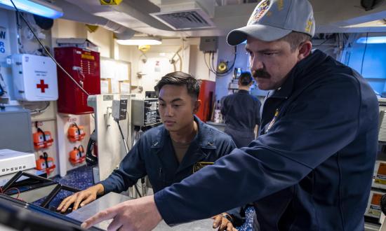 Hull Maintenance Technician First Class Benjamin Cascario, right, trains Lieutenant (junior grade) Jason Punsalan on standing engineering officer of the watch on board the USS John P. Murtha (LPD-26).