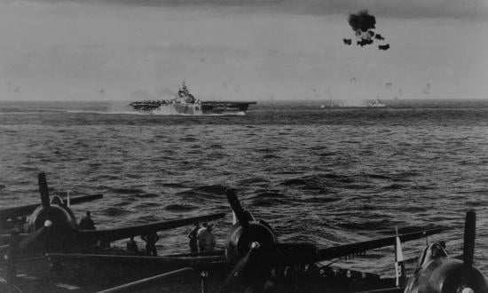 Commander Scott's article was actually written aboard the USS Bennington (above) when the ship was a member of Task Force 58 off Okinawa in 1945. Men on the flight deck of the carrier Hornet in the foreground watch intently as the Bennington has a close call. The kamikaze hits the water between the carrier and the destroyer in the screen.