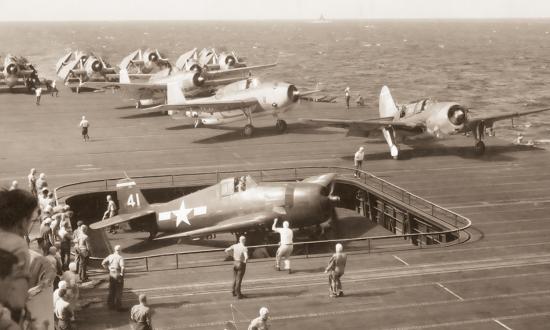 22 October 1944: In the lead-up to the Battle of Leyte Gulf, an F6F Hellcat fighter is raised to the flight deck of the USS Essex as an SB2C Helldiver dive bomber, followed by a TBF Avenger torpedo bomber, prepares to take off.