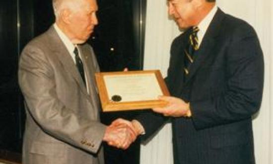 Secretary of the Navy John Dalton, right, congratulates Brast Thomas on becoming a Naval Institute Commodore in April 1996.