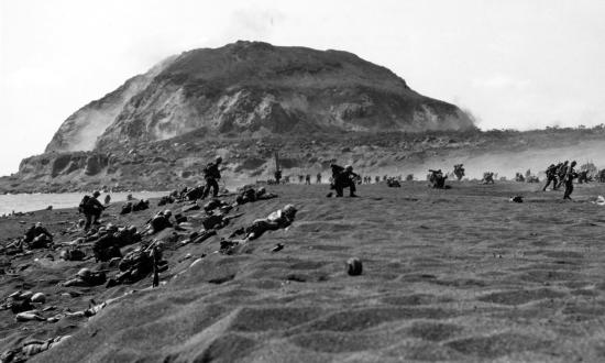 Marines advance in the shadow of Iwo Jima's Mount Suribachi